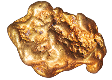Fotografia. Um minério de ouro. Ele tem a coloração amarelada com partes lisas e margens irregulares.