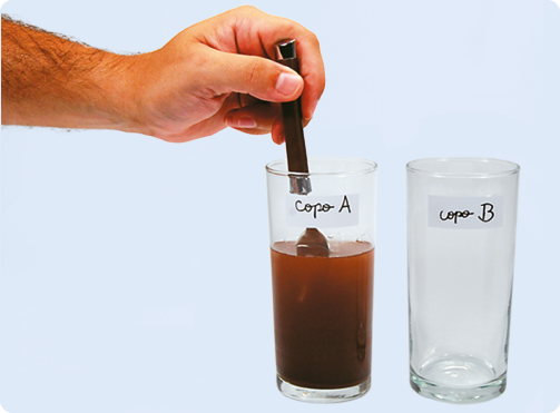 Fotografia de dois copos transparentes. No copo A, uma mão segura uma colher dentro dele com líquido escuro. Ao lado, está o copo B, vazio.