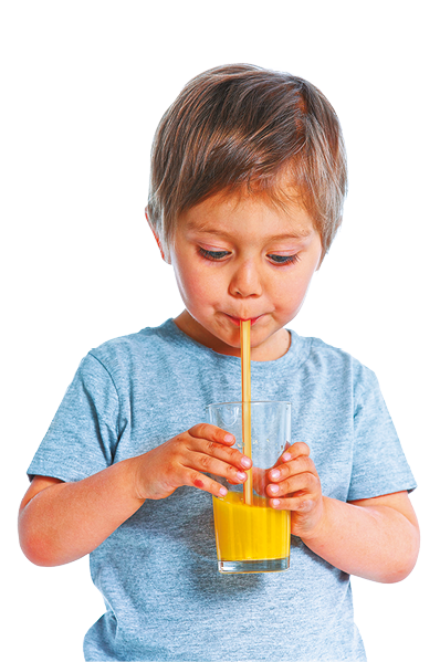 Fotografia de uma criança, vista da cintura para cima, segurando um copo transparente com as duas mãos, que contém um líquido amarelo. Ele está usando um canudo transparente para sugar o líquido do copo, e o canudo está completamente preenchido com o líquido amarelo.