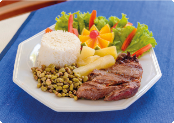 Fotografia de um prato com diferentes alimentos: arroz, feijão, carne, mandioca e salada.