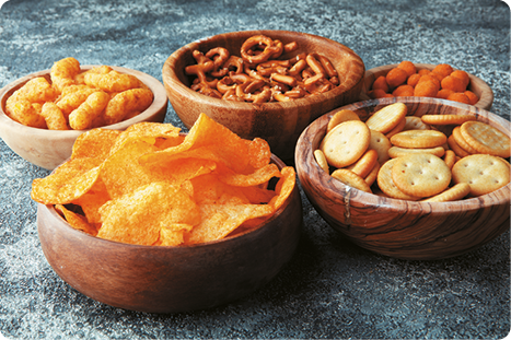 Fotografia de quatro recipientes de madeira com diferentes tipos de biscoitos, amendoins e salgadinhos.