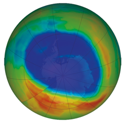 Ilustração. Representação do globo terrestre com o Polo Sul ao centro e a camada de ozônio sobre essa região. Nas laterais, há trechos verdes, amarelos, laranjas e vermelhos. No centro, há uma grande região oval com tom azul.