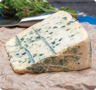 Fotografia de um pedaço triangular de queijo, com furos e manchas de coloração esverdeada em sua superfície.