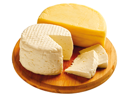 Fotografia com dois tipos diferentes de queijo sobre uma tábua redonda de madeira. Ao fundo, queijo com formato de semicírculo e à frente, um queijo redondo cortado, e ao seu lado, duas fatias.