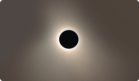 Fotografia do céu, com um círculo completamente preto no centro e ao redor dele um brilho proveniente da luz solar.
