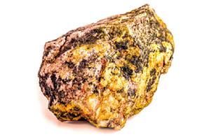Fotografia. Um minério de urânio amarelado com manchas escuras e formato irregular.