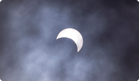 Fotografia do céu com apenas uma porção do Sol visível, com o formato da letra 'C'.