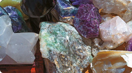 Fotografia. Várias rochas coloridas de formatos irregulares: algumas são brancas, roxas, verdes com manchas escuras e azuis.