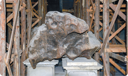 Fotografia de um meteorito, uma rocha amarronzada com formato irregular.