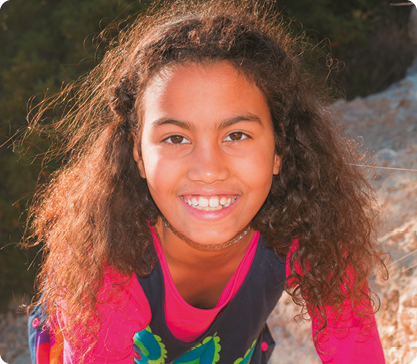 Fotografia do rosto de uma menina com cabelo longo. Na parte superior da testa seu cabelo forma uma linha circular.