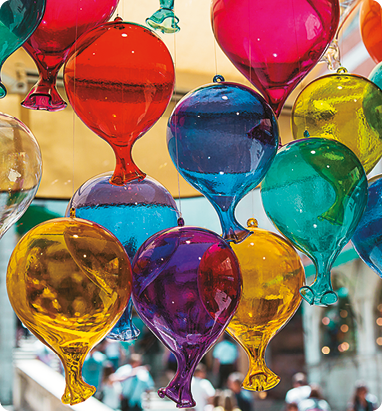 Fotografia. Vários balões coloridos e transparentes pendurados por fios na parte superior.