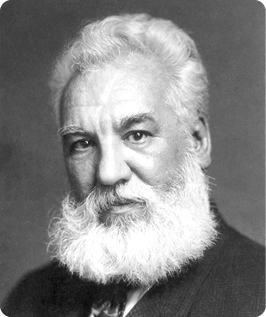 Fotografia em preto e branco de busto de homem com cabelos claros e curtos e uma barba comprida e clara. Ele está usando um terno escuro com gravata.