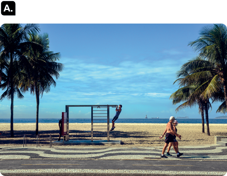 Fotografia A. Destaque para duas pessoas caminhando na calçada de uma praia. Ao fundo, um homem se exercitando em uma estrutura na areia e coqueiros.