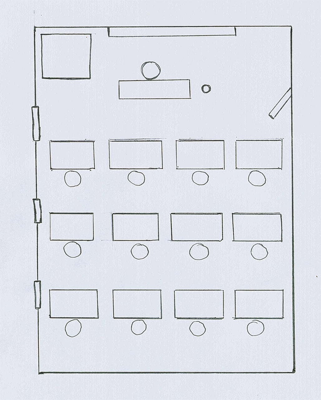 Ilustração. Desenho de uma sala de aula com janelas à esquerda, a lousa, um armário e a mesa do professor na parte superior. Abaixo, as carteiras escolares.