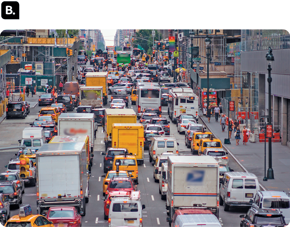 Fotografia B. Uma larga avenida repleta de veículos. Há construções nas laterais.