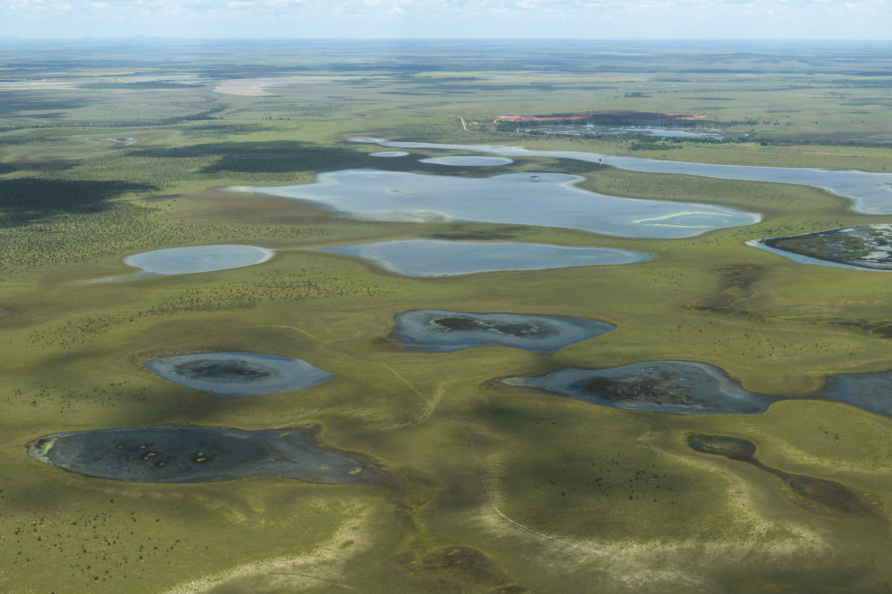 Fotografia A. Vista aérea. Área plana com lagos dispersos e em diferentes tamanhos.