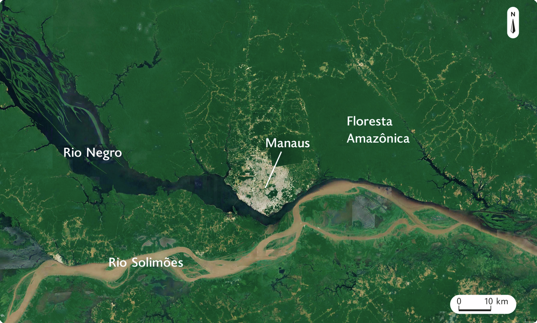 Fotografia. Imagem de satélite mostrando o Rio Solimões e o Rio Negro que se unem compondo um único curso. Na margem central do Rio Negro está Manaus e à direita dela, a Floresta Amazônia. No canto superior direito, seta apontando para o norte, e na parte inferior, a escala: 10 quilômetros por centímetro.