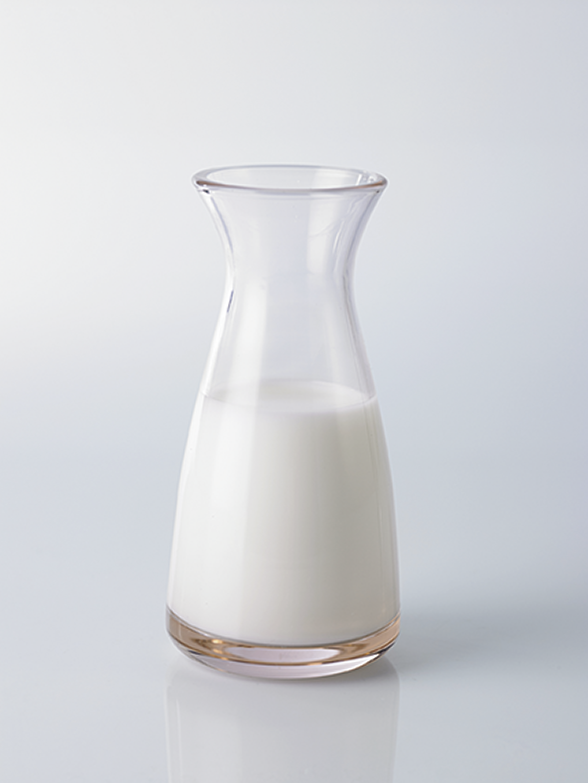 Fotografia. Um jarro com leite em uma bancada.