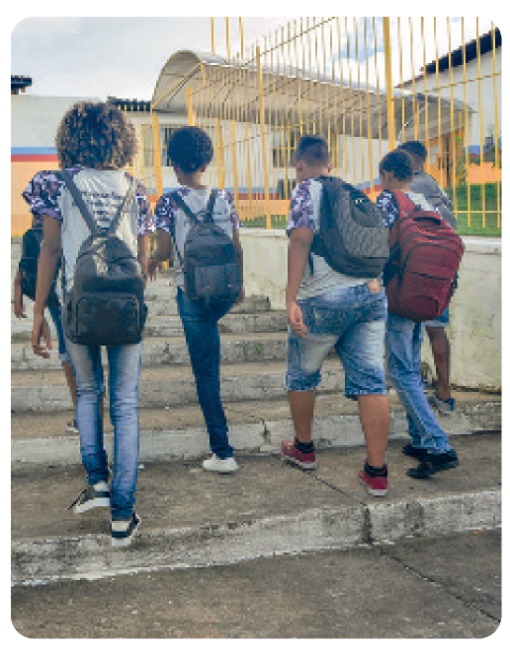 Fotografia. Cinco jovens subindo escadas. Eles carregam mochilas.