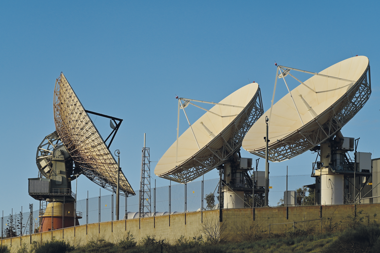 Fotografia. Três grandes antenas apontando em duas direções diferentes.