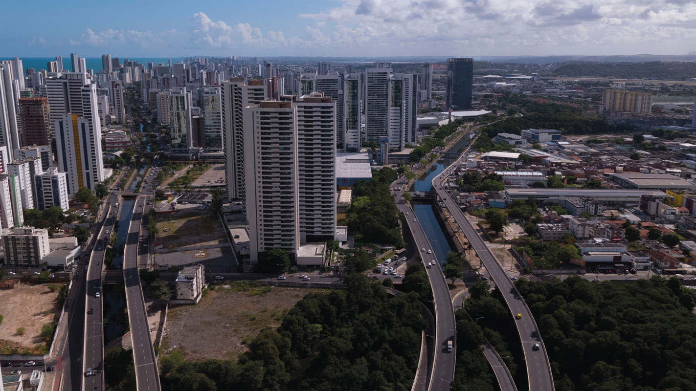 Fotografia. Vista de cima. Cidade com muitos edifícios e vias nas margens de rios.