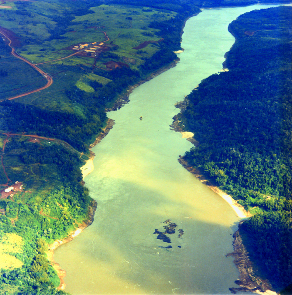 Fotografia. Vista aérea. Curso de um rio com as margens repletas de vegetação.