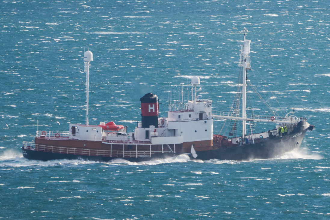 Fotografia. Um barco com mastros e outras estruturas navegando no mar azul.