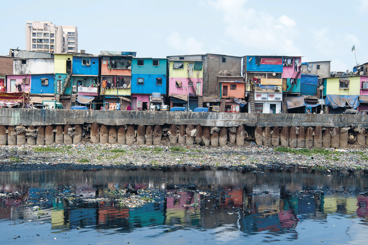 Fotografia. Casas coloridas sobrepostas na margem de um rio.