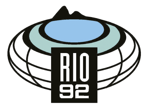 Símbolo Rio 92 com uma estrutura circular com o mar e orla ao centro. Ao fundo, morros.
