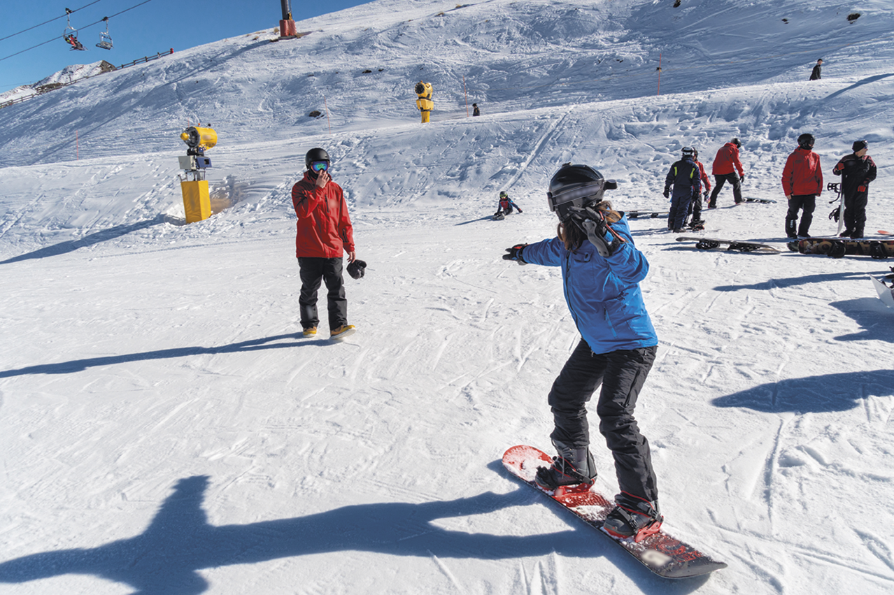 Fotografia. Pessoas praticando esportes em uma montanha coberta por neve.