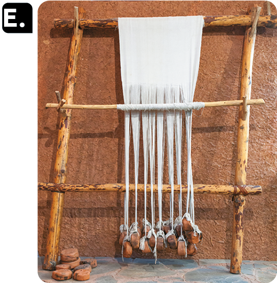 Fotografia E. Um suporte de madeira com um tecido em tiras pendurado.