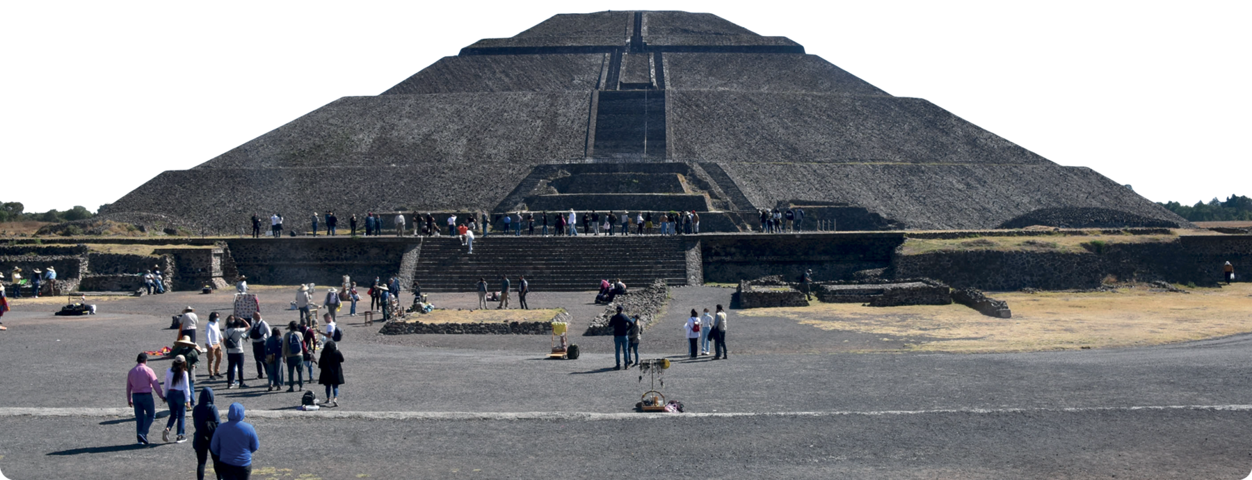 Fotografia. Uma pirâmide de pedra com uma escadaria central. Na frente, diversas pessoas olhando para a pirâmide e nas escadarias.
