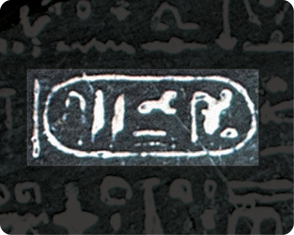 Fotografia. Destaque de recorte da Pedra de Roseta com elementos de escrita em hieróglifo.