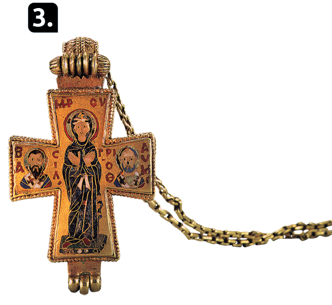 Fotografia 3. Uma cruz dourada com  uma pessoa com os braços cruzados e um círculo ao redor da cabeça. Em cada lateral da cruz, há o busto de uma pessoa.