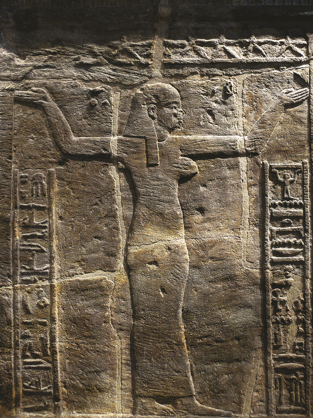 Relevo. Silhueta de uma mulher com os braços erguidos para cima. Nas laterais, ideogramas dispostos verticalmente.