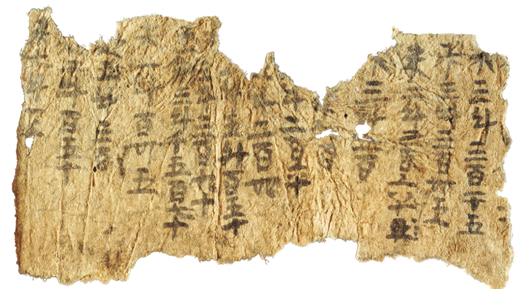 Fotografia. Um pedaço de papel com elementos da escrita chinesa. Ele apresenta desgaste por conta da passagem do tempo.
