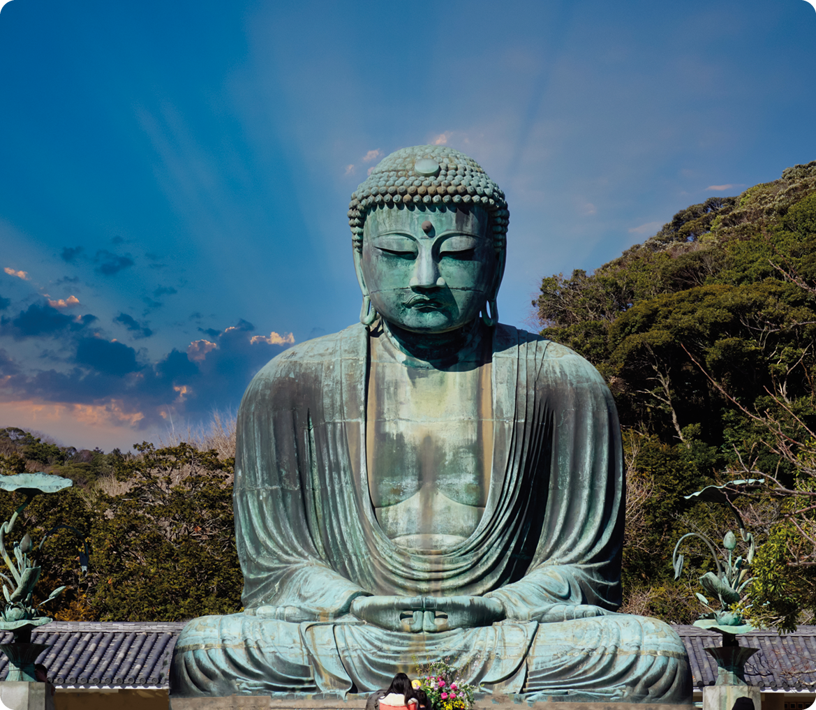 Fotografia. Estátua do Buda, homem  usando tecido ao redor do corpo e uma pedra no meio da testa. Ele está sentado, com as pernas cruzadas, as mãos juntas sobre as pernas e os olhos fechados.