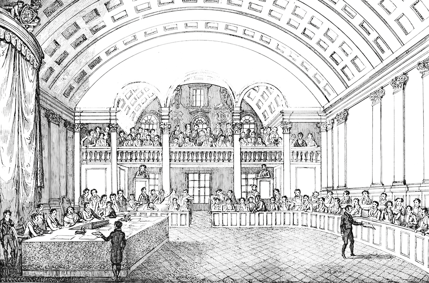 Gravura em preto e branco. Vista de um cômodo grande decorado com colunas e arcos. À esquerda, uma mesa grande com pessoas sentadas. Ao redor, uma bancada em meia lua com pessoas sentadas. Ao fundo, na parte superior, um mezanino com pessoas sentadas.