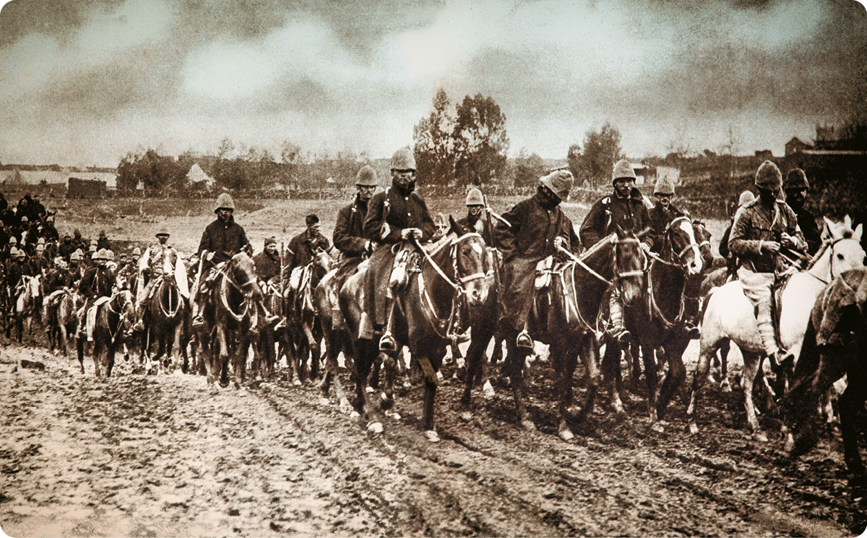 Fotografia em tons de sépia. Diversos homens usando capacete e farda sobre cavalos enfileirados.