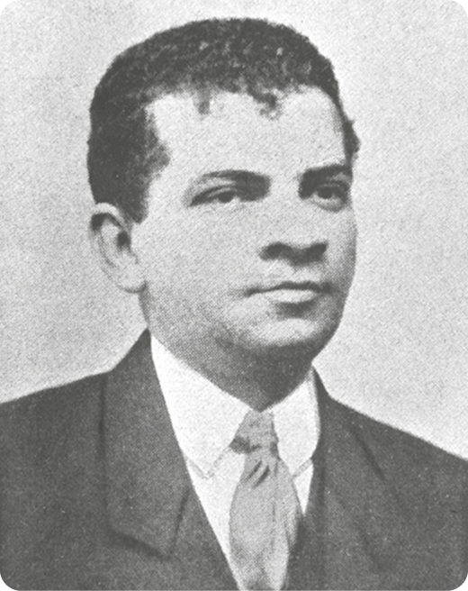 Fotografia em preto e branco. Destacando o busto de um homem, usando terno e gravata.