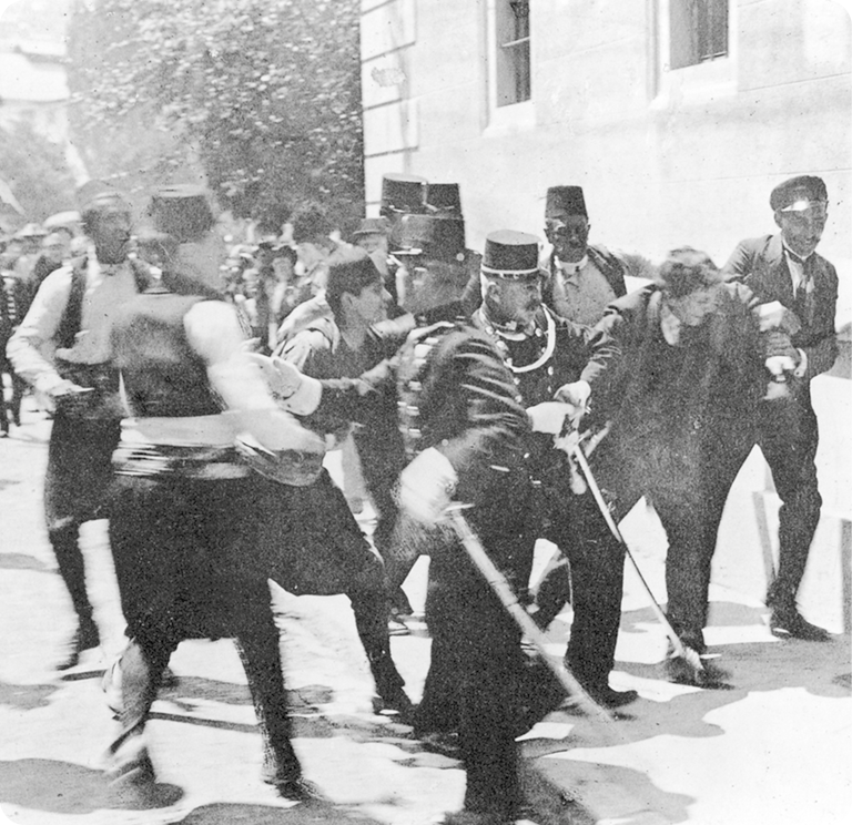 Fotografia em preto e branco. Um homem, usando terno, está sendo carregado pelos braços por dois homens fardados.