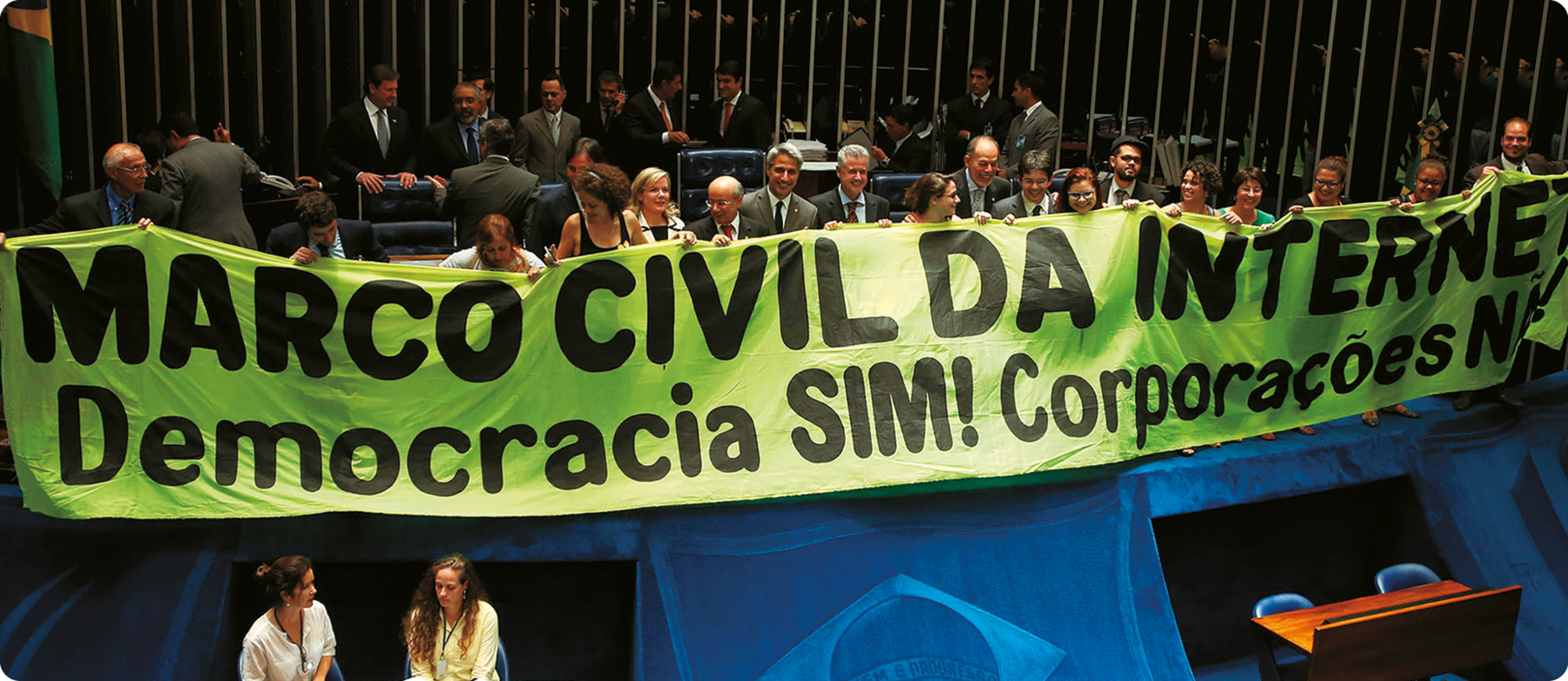Fotografia. Homens e mulheres segurando uma grande faixa com o texto: MARCO CIVIL DA INTERNET. Democracia SIM! Corporações NÃO!