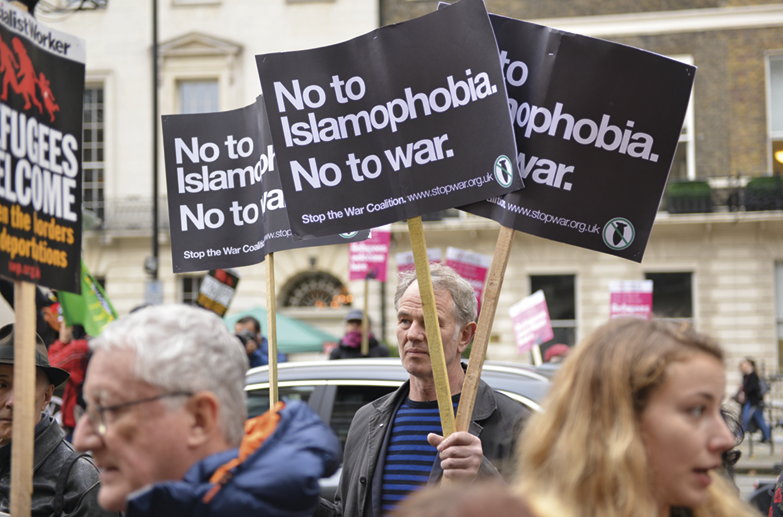 Fotografia. Algumas pessoas segurando cartazes e placas com o texto: NO TO ISLAMOPHOBIA. NO TO WAR.
