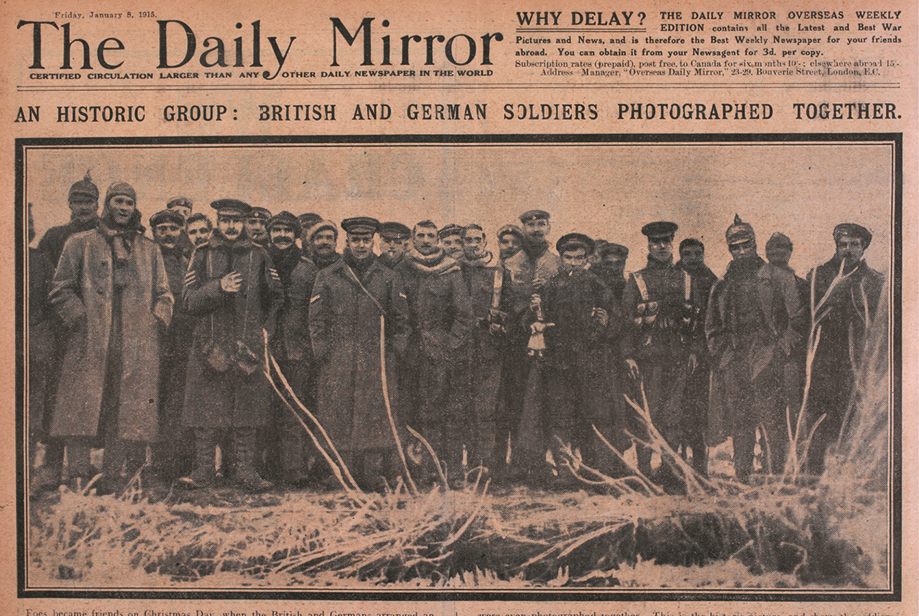 Jornal. Na parte superior, o nome do Jornal: The Daily Mirror. Abaixo, do título, o texto: AN HISTORIC GROUP: BRITISH AND GERMAN SOLDIERS PHOTOGRAPHED TOGHETER.  Ao centro, fotografia de uma grupos de soldados usando chapéu e casaco. Eles estão de pé, um do lado do outro.