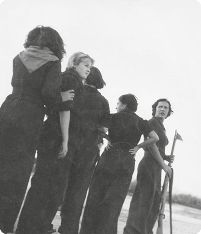 Fotografia em preto e branco. Cinco mulheres usando roupas pretas. Elas estão de pé e em fila.