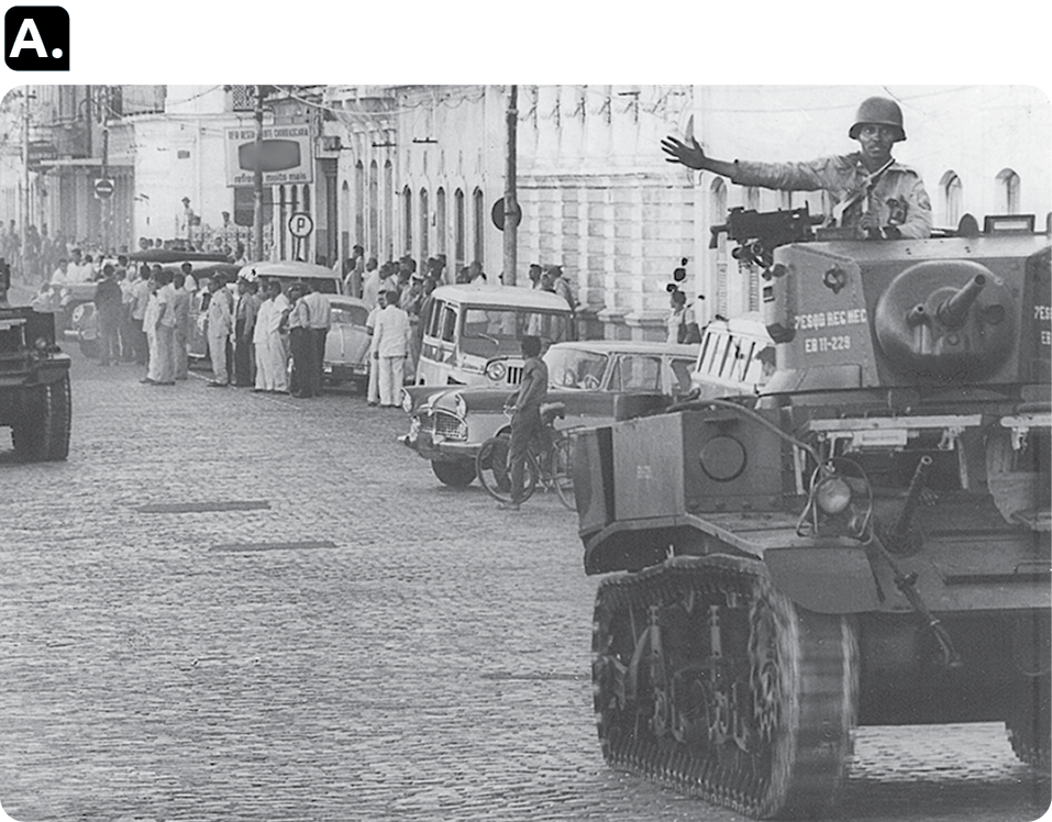 Fotografia em preto e branco 'A'. No primeiro plano, à direita, um tanque de guerra com um soldado dentro.  Ao fundo, várias pessoas em pé perto de veículos.