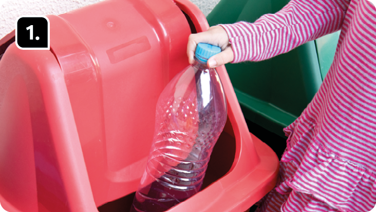 Fotografia '1'. Destacando a mão de uma criança segurando uma garrafa plástica em uma lata de lixo vermelha.