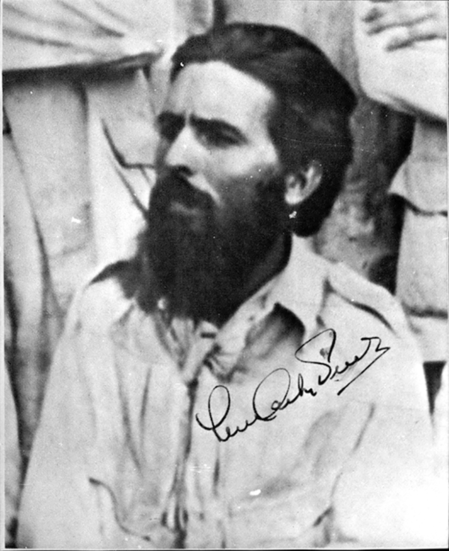 Fotografia em preto e branco. Destaca o busto de homem com cabelos e barba preta. No canto inferior direito, há a assinatura de Luís Carlos Prestes.