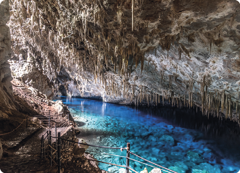 Fotografia de uma gruta com sua água com vários tons de azul refletidos.