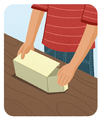 Ilustração das mãos de um menino desmontando uma caixa de papel, de formato de um paralelepípedo reto retângulo, que está em cima de uma mesa. Nesse momento o menino está abrindo as faces laterais da caixa.